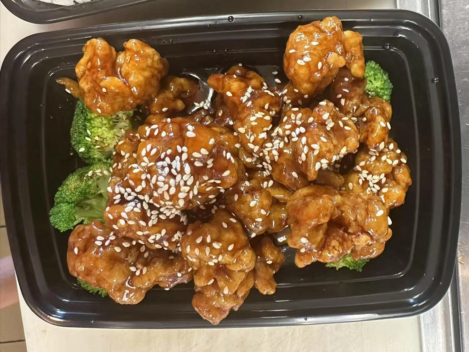 Sesame - covered chicken with broccoli in tray at Taste of China,a Chinese restaurant in Raleigh.